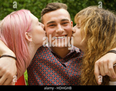 Vista laterale di donne baciare uomo sulle guance in cantiere Foto Stock