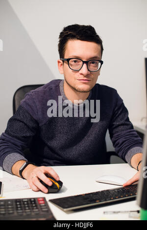 Ritratto di sorridente imprenditore informale a lavorare con il computer in ufficio Foto Stock