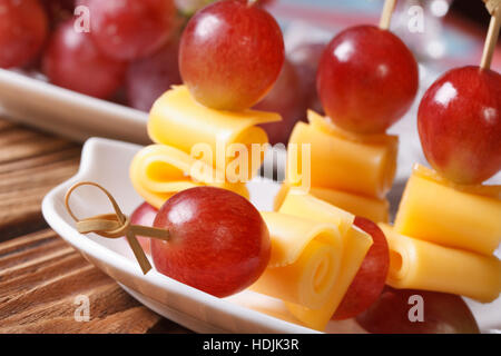Finger food: uva e formaggio su spiedini macro su una piastra orizzontale. Foto Stock