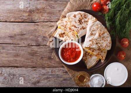 Quesadilla affettata con verdure e salse sul tavolo. vista orizzontale dal di sopra Foto Stock