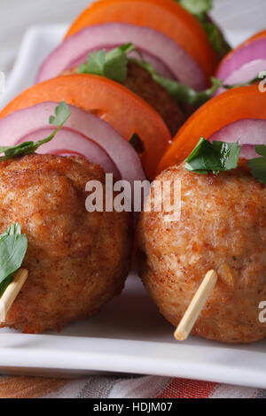 Polpette fritte su spiedini con verdure fresche su una piastra macro verticale. Foto Stock