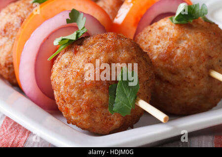 Le polpette di carne arrosto su spiedini con verdure fresche su una piastra macro. orizzontale Foto Stock