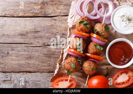 Le polpette di carne arrosto su spiedini e verdure fresche su un vecchio tavolo. vista orizzontale dal di sopra, stile rustico Foto Stock