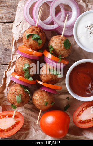 Le polpette di carne arrosto su spiedini e verdure fresche su un vecchio tavolo. vista verticale dal di sopra, stile rustico Foto Stock