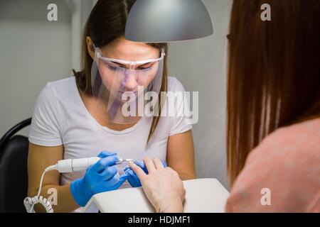Il master utilizza una macchina elettrica per rimuovere le unghie Foto Stock