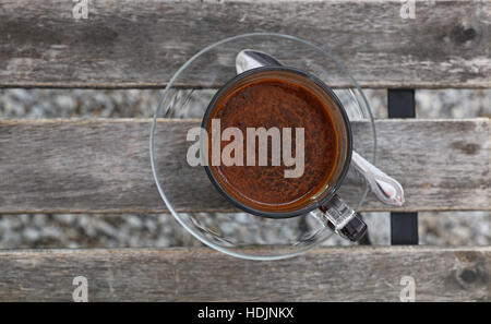 Bagno turco preparato di fresco terreno naturale, caffè schiuma marrone schiuma in vetro trasparente tazza con piattino su vintage tavolo in legno, close up, elevati top Foto Stock