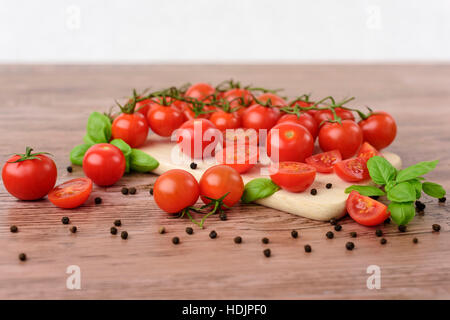 Mini tomaotes sul tavolo di legno con sfondo luminoso. Foto Stock