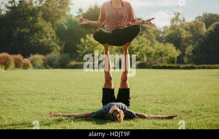 Forte coppia giovane facendo acroyoga all'esterno. L uomo e la donna nel parco coppia pratica yoga pone. Foto Stock