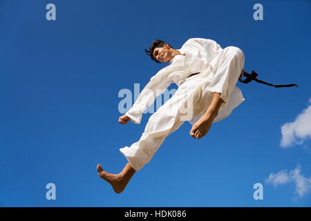 Giovani, atleta, attività sportiva, combattere e sport estremi. Uomo ispanico che esercitano nel Karate e arti marziali tradizionali, saltando metà-aria in t Foto Stock