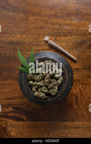 La Cannabis sativa boccioli di fiori in vaso di legno con giunto di laminati su sfondo di legno Foto Stock