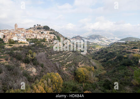 Polop, Provincia di Alicante, Spagna vista da lontano di una fortezza collinare e la città, con le case, la chiesa e il castello Foto Stock