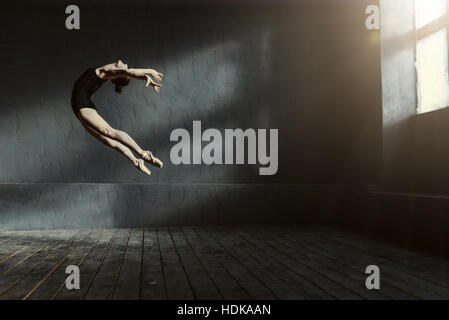 Professional ballerina di eseguire nella buia stanza illuminata Foto Stock