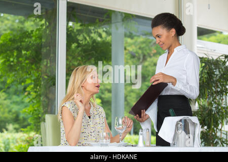 Cameriera mostra menu per cena femmina Foto Stock