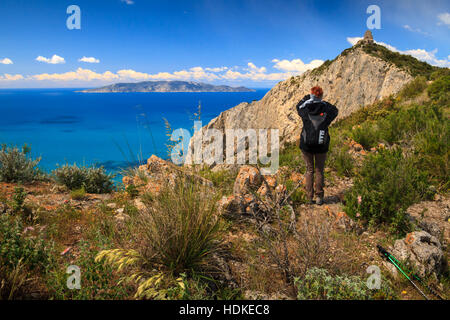 Monte Argentario, Aprile 2016: Donna facendo trekking e guardare l'isola del Giglio dalla costa toscana in una giornata di sole , in aprile 2016 a Monte Argentario Foto Stock