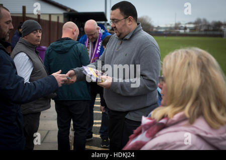Uno spettatore di acquistare un programma di confronto al Delta Taxi Stadium, Bootle, Merseyside prima che la città di Liverpool ha ospitato Holker Old Boys in un nord ovest contee League Division una partita. Fondata nel 2015, e mira ad essere il premier non-League Club di Liverpool, in città sono state ammesse al campionato all'inizio della stagione 2016-17 e sono state usando Bootle FC di massa per partite in casa. Una vittoria 6-1 sopra i loro visitatori hanno preso "Purps' alla sommità della divisione, in una partita controllata da 483 spettatori. Foto Stock