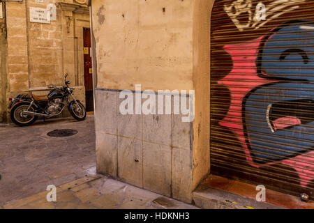 I graffiti sulla parete del garage in una tranquilla stradina con stile vecchia motocicletta Foto Stock