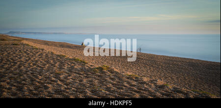 Di pescatori lungo Chesil Beach guardando verso Weymouth e Portland, Dorset, England, Regno Unito Foto Stock