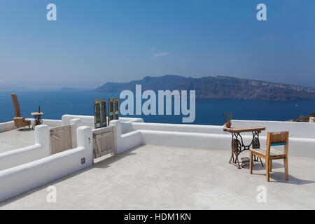 Vuoto terrazzo con tavoli e sedie che si affaccia su un mare blu, Oia - Santorini, Grecia. Foto Stock