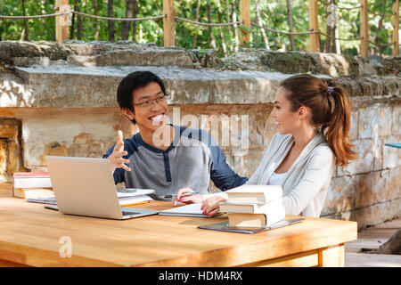 Felice giovane coppia di studenti che studiano con il computer portatile all'aperto e ridere Foto Stock
