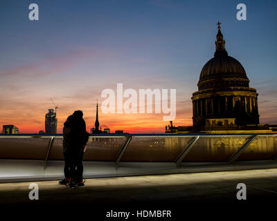 Un giovane abbraccia con la skyline di Londra dietro di loro al tramonto Foto Stock