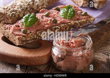 Sandwich con pate, capperi e basilico close-up sul tagliere orizzontale. Foto Stock