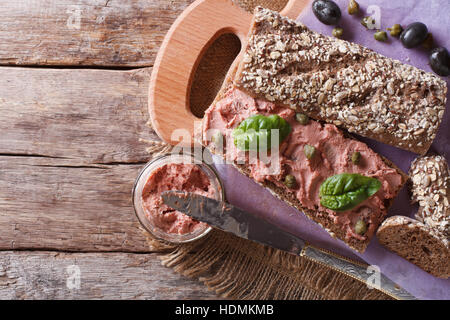 Sandwich con pate, capperi e basilico close-up sul tagliere. vista orizzontale dal di sopra Foto Stock