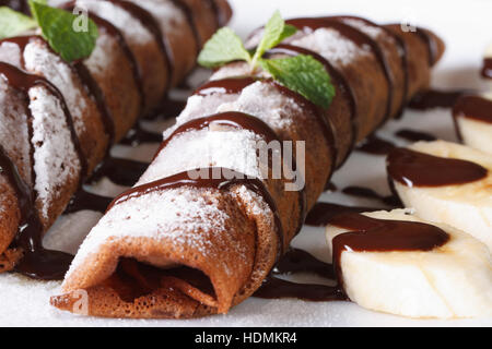 Frittelle al cioccolato con salsa di pomodoro e banana su una piastra macro. orizzontale Foto Stock