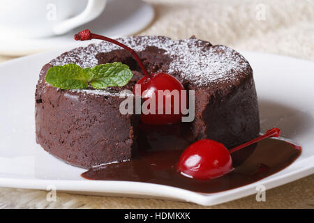 Cioccolato fondente torta con ciliegie e macro di menta su una piastra e caffè. Posizione orizzontale Foto Stock