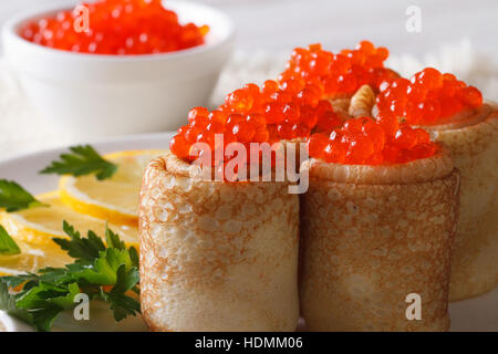 Crepes panini farciti con caviale rosso su una piastra macro. orizzontale Foto Stock