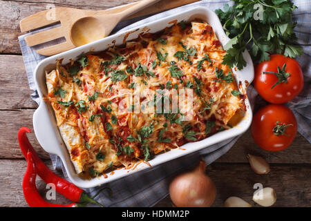 Enchilada messicano in una teglia con gli ingredienti sul tavolo di close-up. vista orizzontale dal di sopra Foto Stock