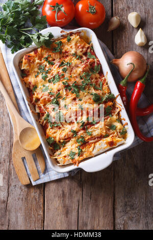 Enchilada messicano in una teglia con gli ingredienti sul tavolo. vista verticale da sopra Foto Stock