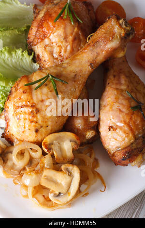 Fritto di pollo Cosce di pollo disossate con funghi e rosmarino sulla piastra closeup. verticale vista superiore Foto Stock