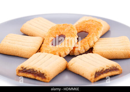 Biscotti dolci con marmellata su lastra grigia su sfondo bianco. Foto Stock
