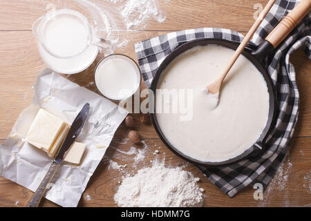 Preparazione della salsa besciamella in una padella e gli ingredienti sul tavolo. vista orizzontale dal di sopra Foto Stock