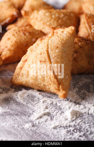 Un mucchio di cottura samosas su un tavolo infarinato. verticale di close-up Foto Stock