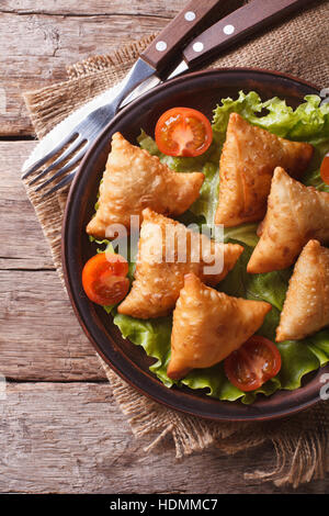 Una deliziosa pasticceria samosa su una piastra di close-up. vista verticale al di sopra, stile rustico Foto Stock