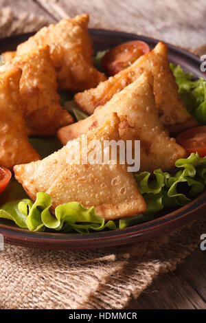 Samosa su una piastra con pomodori e lattuga su un tavolo di legno. Verticale di close-up Foto Stock