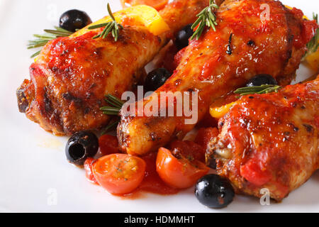 Fried le cosce di pollo in salsa di pomodoro con peperoni e olive e rosmarino su una piastra bianca, horizontal macro Foto Stock