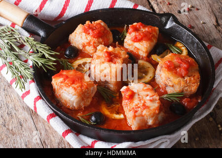 Filetto di pesce in salsa di pomodoro in una padella e gli ingredienti sul tavolo orizzontale. Foto Stock