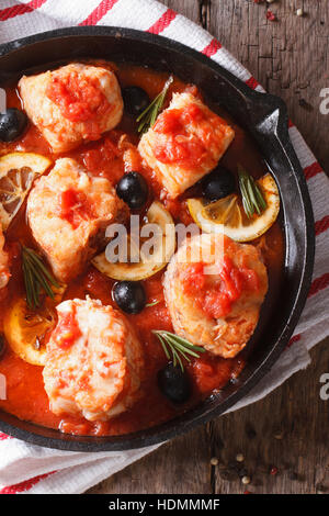 Filetto di pesce in salsa di pomodoro in una padella vicino sul tavolo. verticale vista superiore Foto Stock