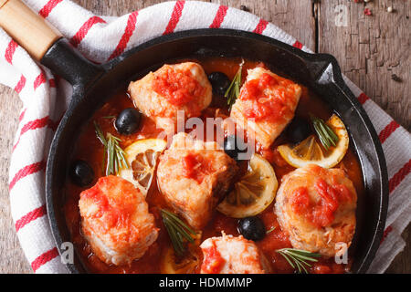 Filetto di pesce in salsa di pomodoro in una padella vicino sul tavolo. Orizzontale vista superiore Foto Stock