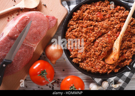 Il ragù alla bolognese in una padella con gli ingredienti sul tavolo. vista orizzontale dal di sopra closeup Foto Stock
