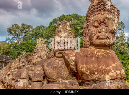 Asura statue tenere il Cobra snake divinità Naga sul lato della strada che conduce alla porta sud del Ta Prohm, Cambogia. Foto Stock