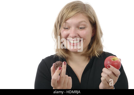 Sorridente giovane donna esitando tra un cioccolato e un apple Foto Stock