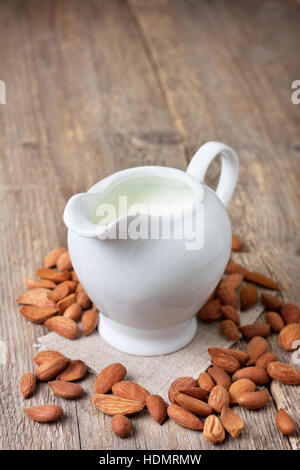 Latte di Mandorla nella brocca del latte di mandorla , sul vecchio sfondo di legno Foto Stock