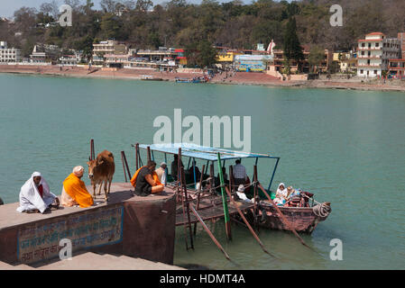 Gente seduta sul molo del traghetto in attesa di barca,Rishikesh, India Foto Stock