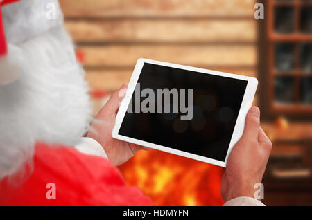 Santa Claus holding tablet con schermo isolato per mockup. Il camino in background. Foto Stock