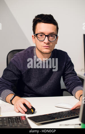 Ritratto di sorridente imprenditore informale a lavorare con il computer in ufficio Foto Stock