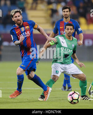 Doha in Qatar. Xiii Dec, 2016. Barcellona il Lionel Messi (L) il sistema VIES per la sfera con Al Ahli Arabia's adattare al Jassim durante la loro cordiale partita di calcio a Doha, capitale del Qatar, Dic 13, 2016. Barcellona ha vinto 5-3. Credito: Nikku/Xinhua/Alamy Live News Foto Stock