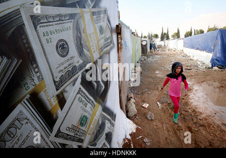 Un rifugiato siriano ragazza cammina attraverso il campo di rifugiati dove vive nella valle della Bekaa, Libano, vicino alla frontiera siriana. Foto Stock
